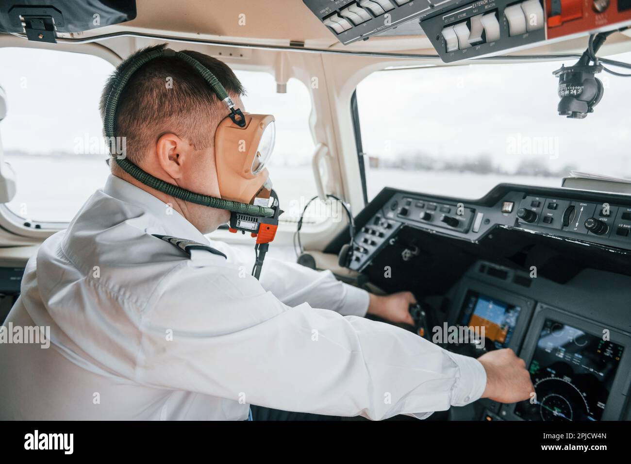 In oxygen mask. Pilot on the work in the passenger airplane. Preparing
