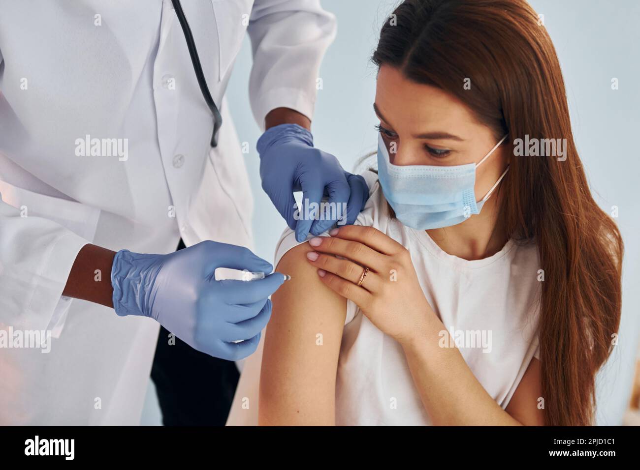 Young african american doctor giving injection to woman at hospital ...