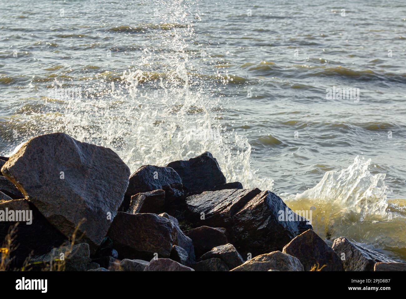 a beautiful seashore with a wave and big stones, the waves break on the ...