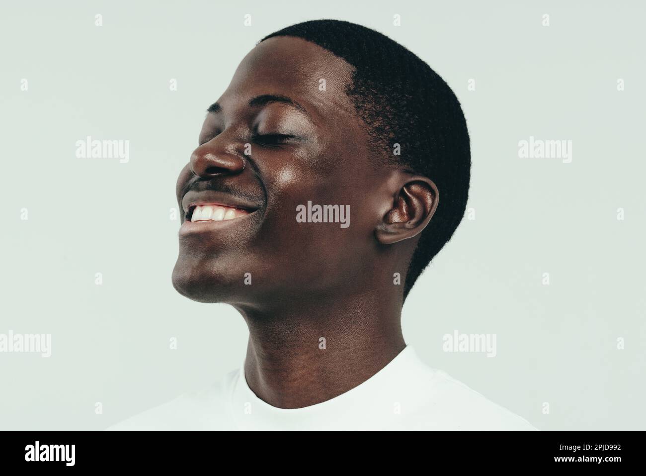 Happy young man celebrating his beautiful and glowing melanin skin with a smile. Youthful black male showing off the radiance he has achieved from a h Stock Photo