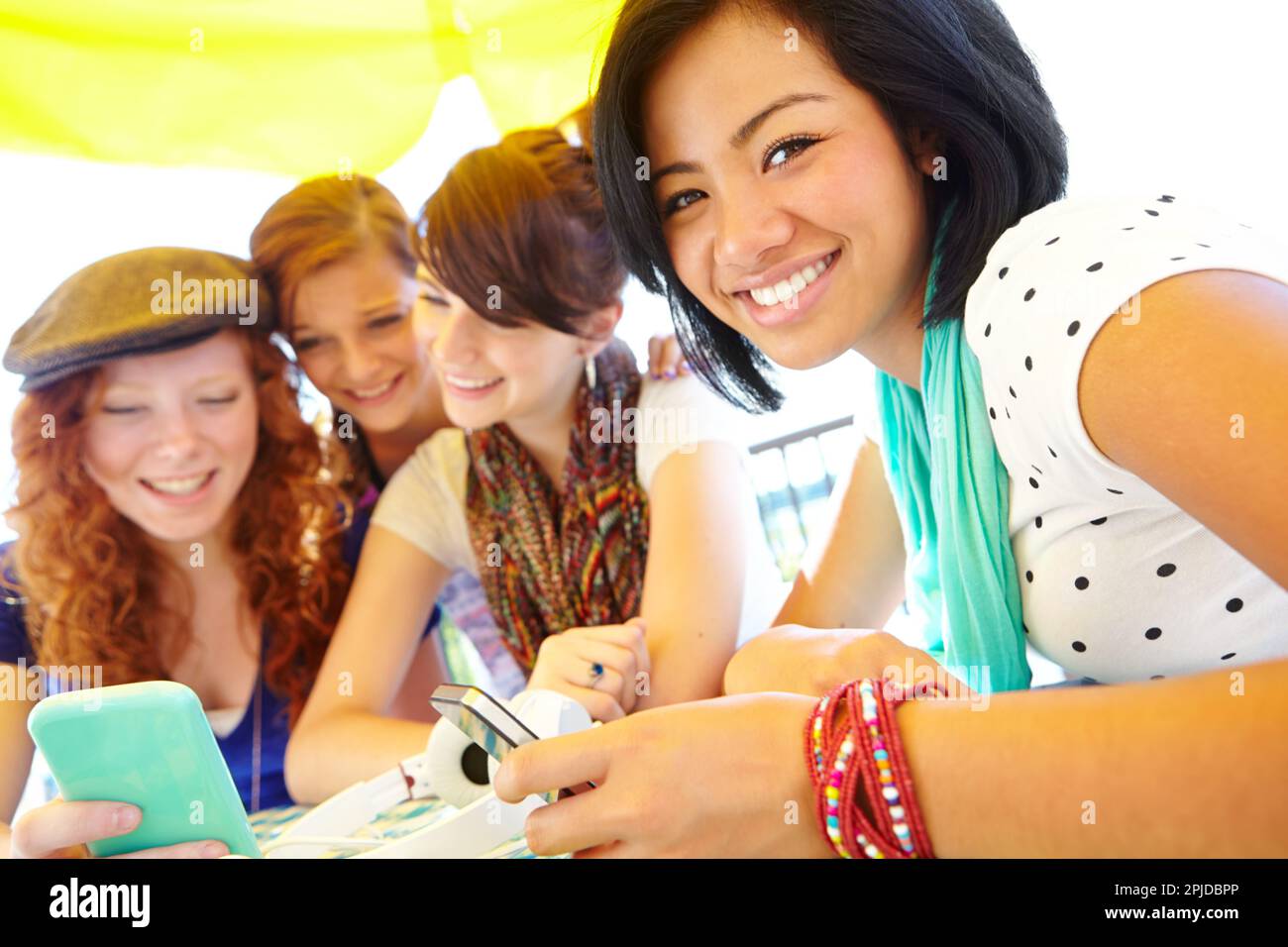 Its hard to separate a girl fro her gadgets. A group of adolescent girls laughing as they look at something on a smartphone screen. Stock Photo