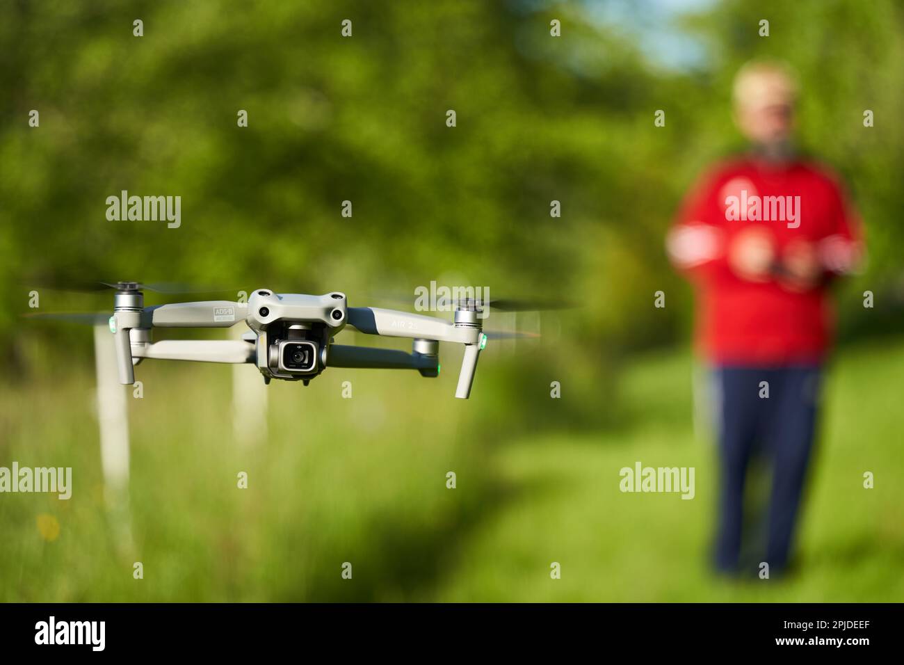 Nürtingen, Germany - May 29, 2021: The drone Dji air 2s. Grey unmanned aircraft system hovers over a green meadow. Pilot out of focus in background. F Stock Photo