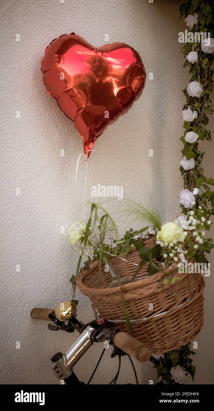 heart shaped balloon and flower garland attached to a bicycle handlebar