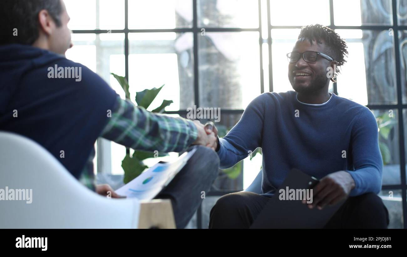 a black man with a folder in his hands shakes hands Stock Photo