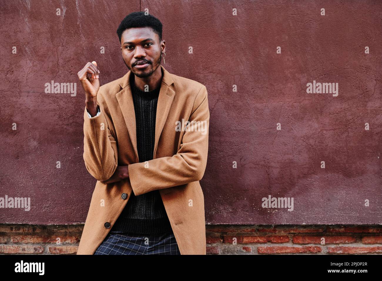 Stylish black man looking at camera with a serious face while posing outdoors. Stock Photo