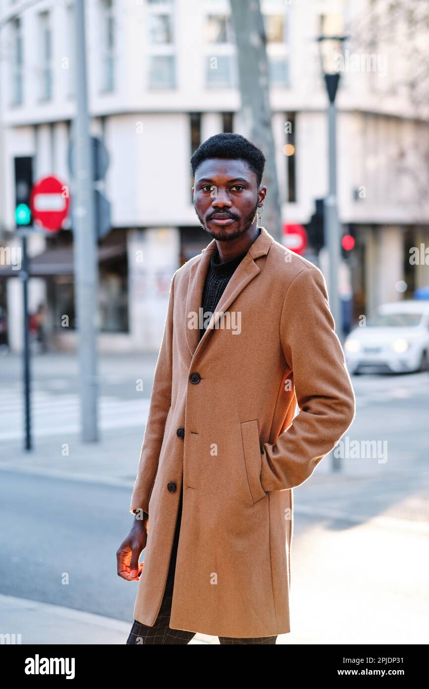 Stylish confident African American man looking at camera while posing standing outdoors in the street. Stock Photo