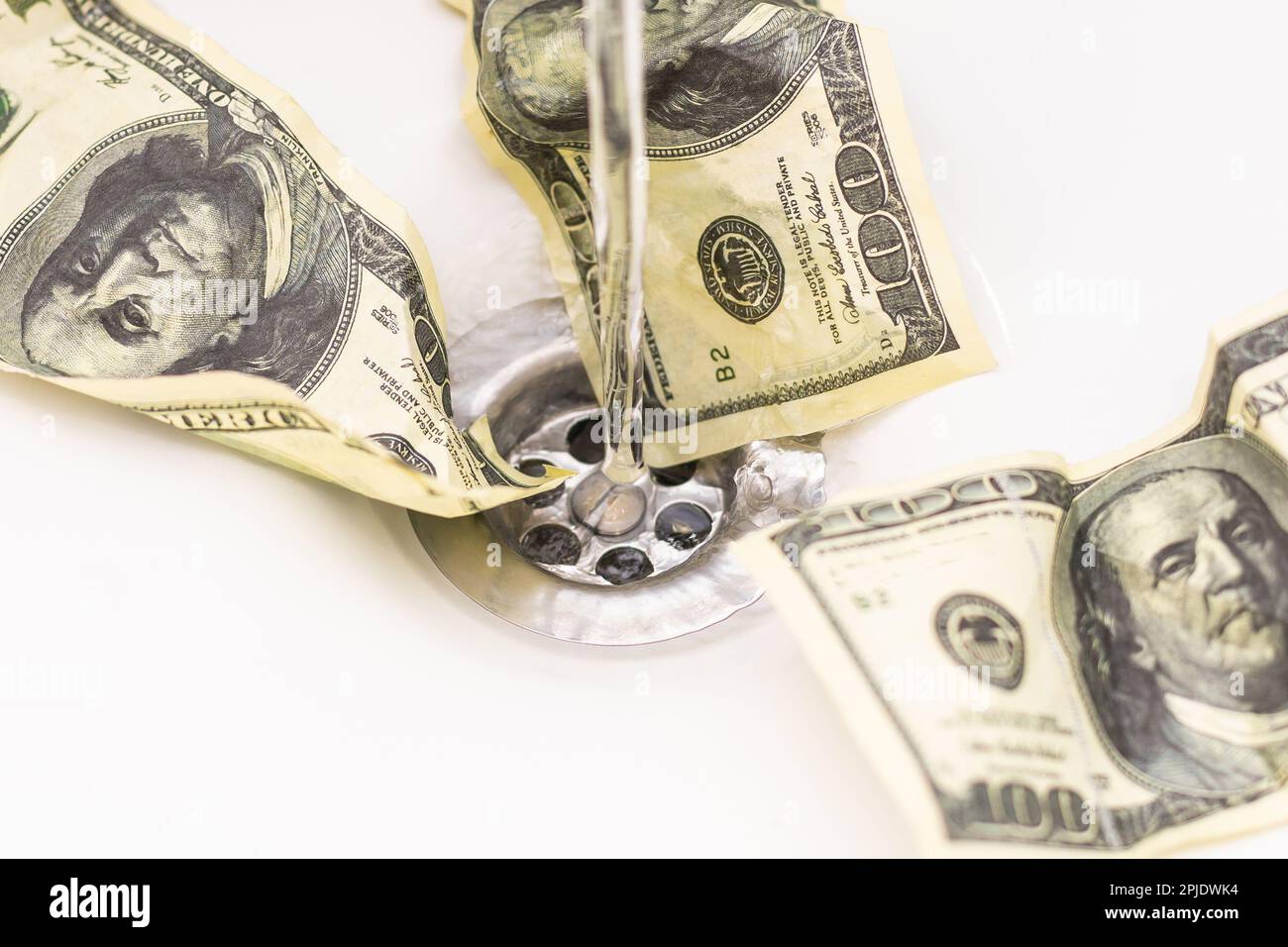 Cash Money Going Down Sink Drain Isolated on White Background Stock