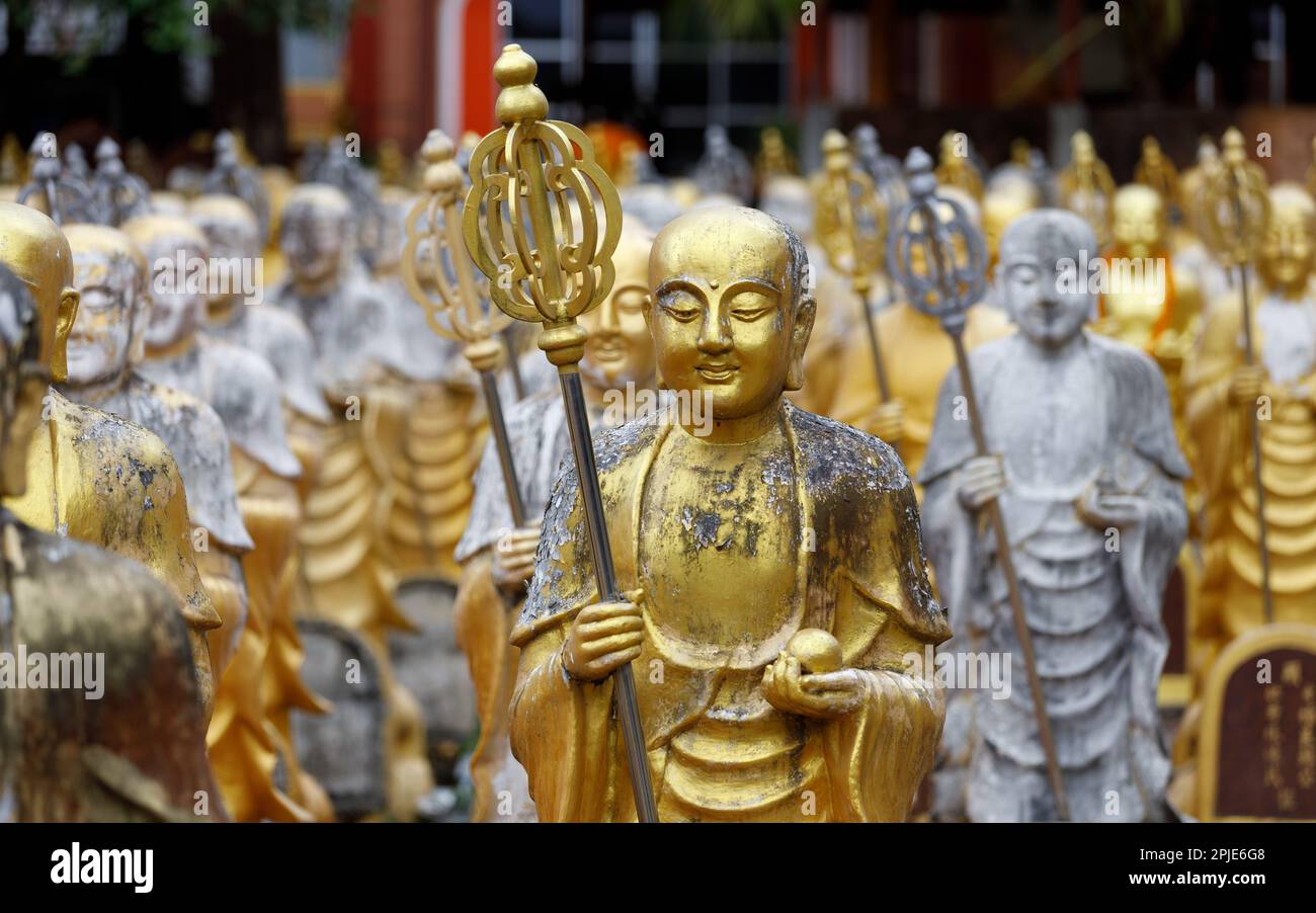 Gold Buddhist Monk statues. Kṣitigarbha monk statues holding khakkhara or tiger pewter staffs. Mahayana Buddhism. Guardians of cemeteries. Stock Photo