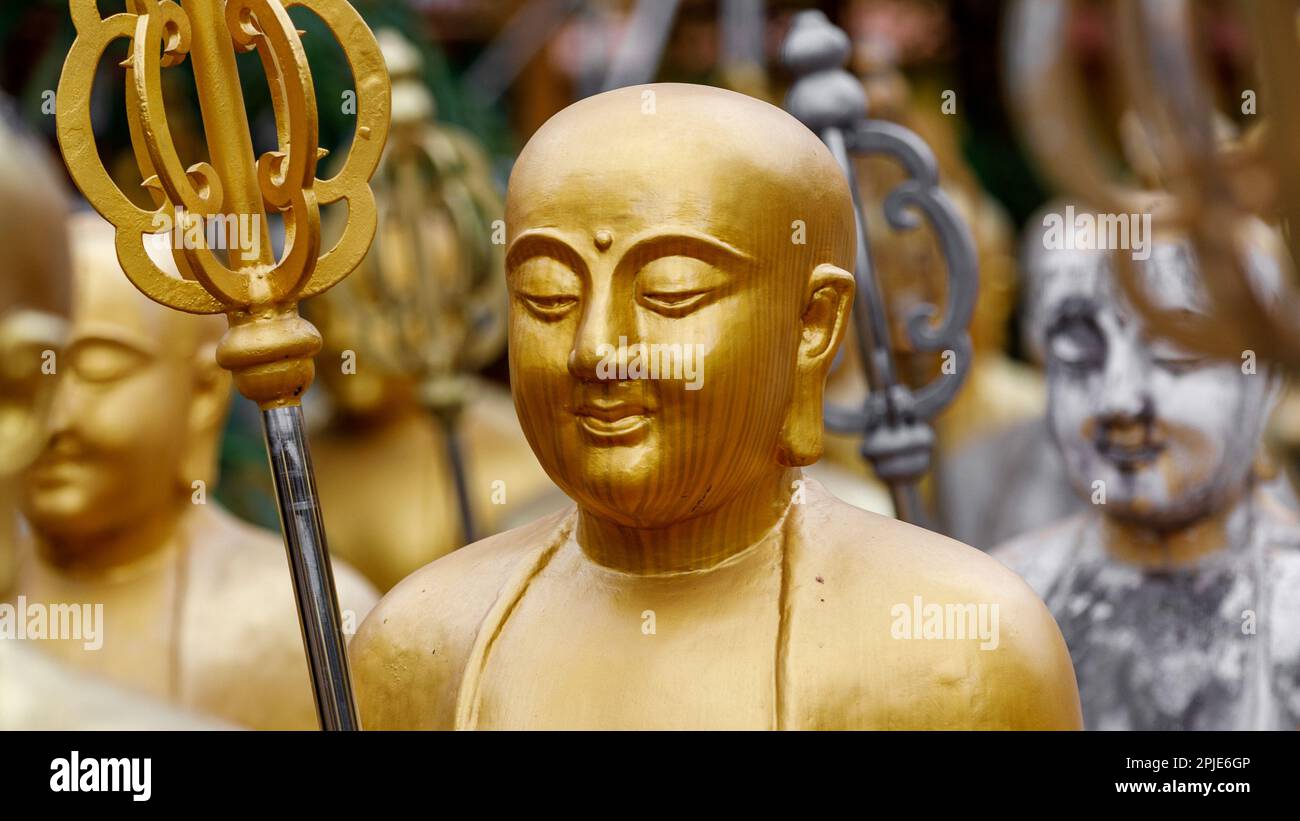 Buddhist statue of gold monks. Kṣitigarbha monk statues holding khakkhara or tiger pewter staffs. Mahayana Buddhism. Guardians of cemeteries. Stock Photo