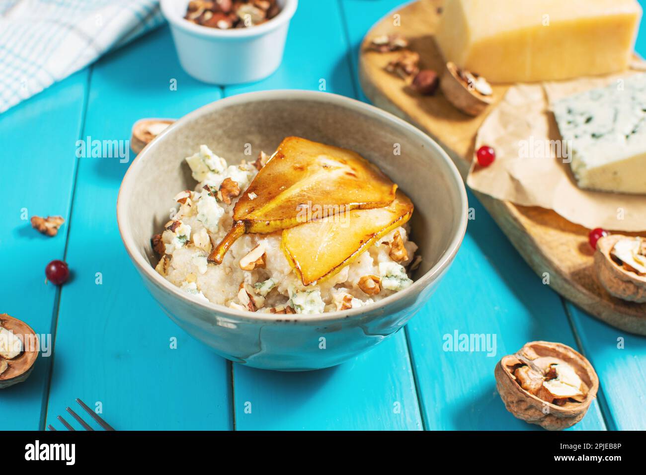 Pear and gorgonzola oatmeal with walnuts on blue wooden table. Stock Photo