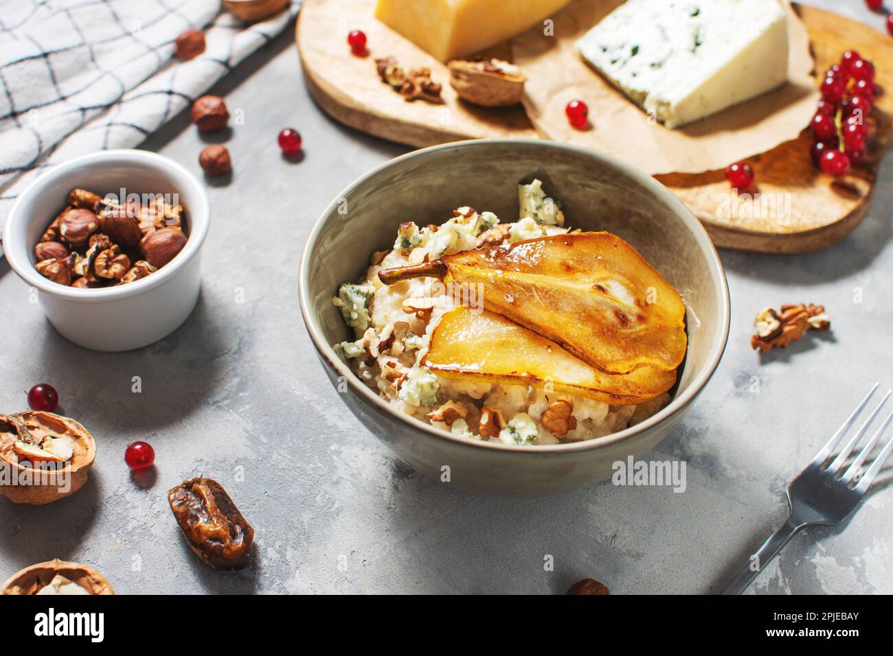 Pear and gorgonzola oatmeal with walnuts on concrete table. Stock Photo