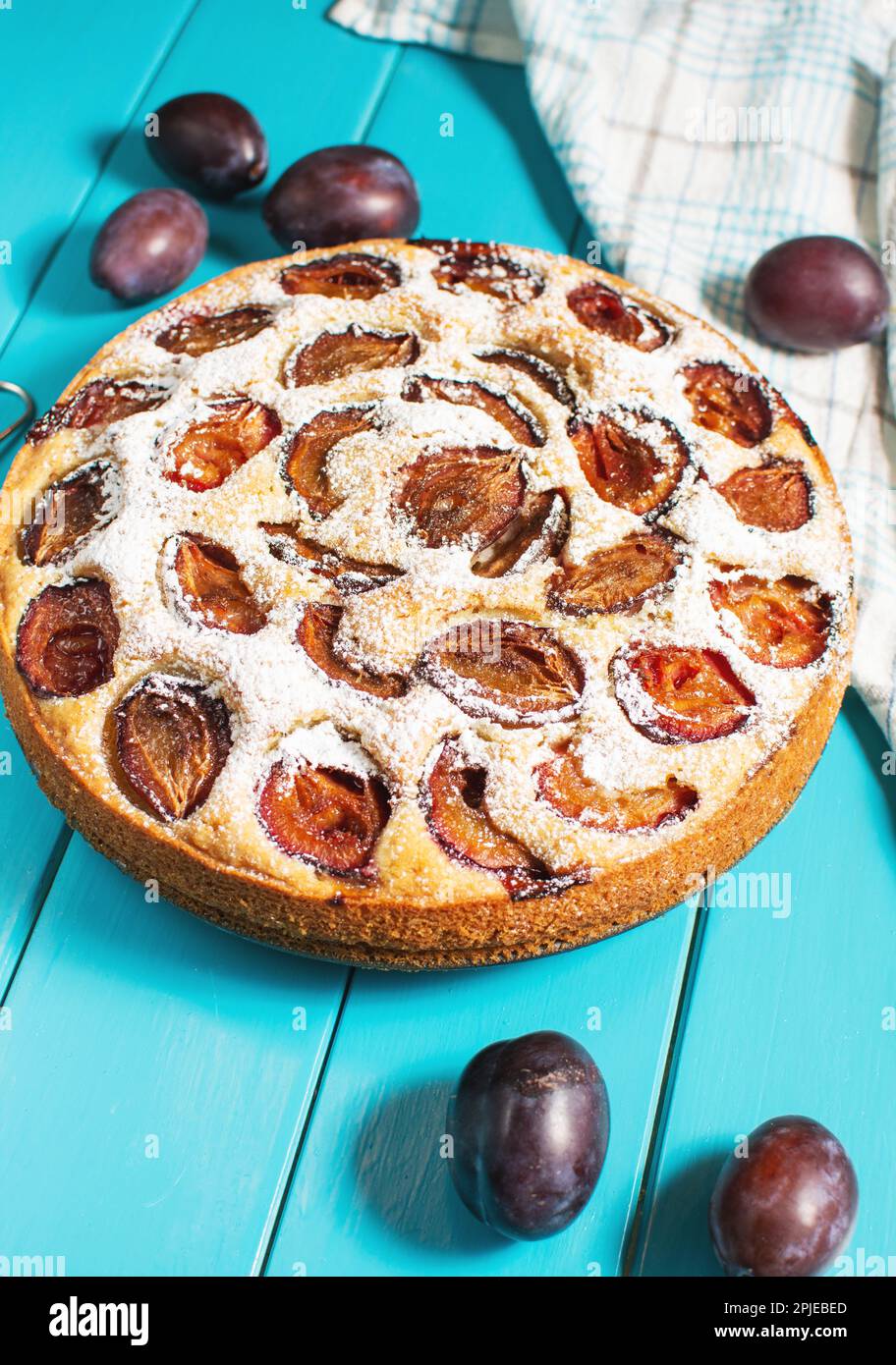 Homemade delicious plum tart with with sugar powder on blue wooden table Stock Photo