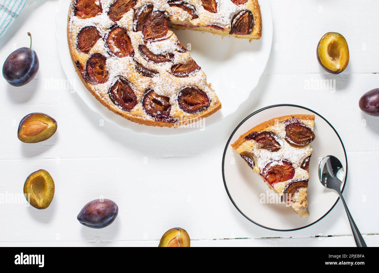 Homemade delicious plum tart with with sugar powder on white wooden table. Top view Stock Photo