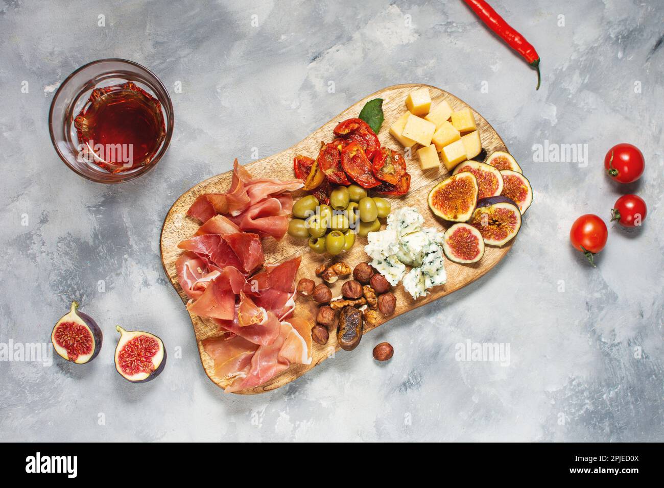 Antipasto platter with ham, prosciutto, blue cheese, dried tomatoes, figs and olives on a wooden bord. Top view Stock Photo