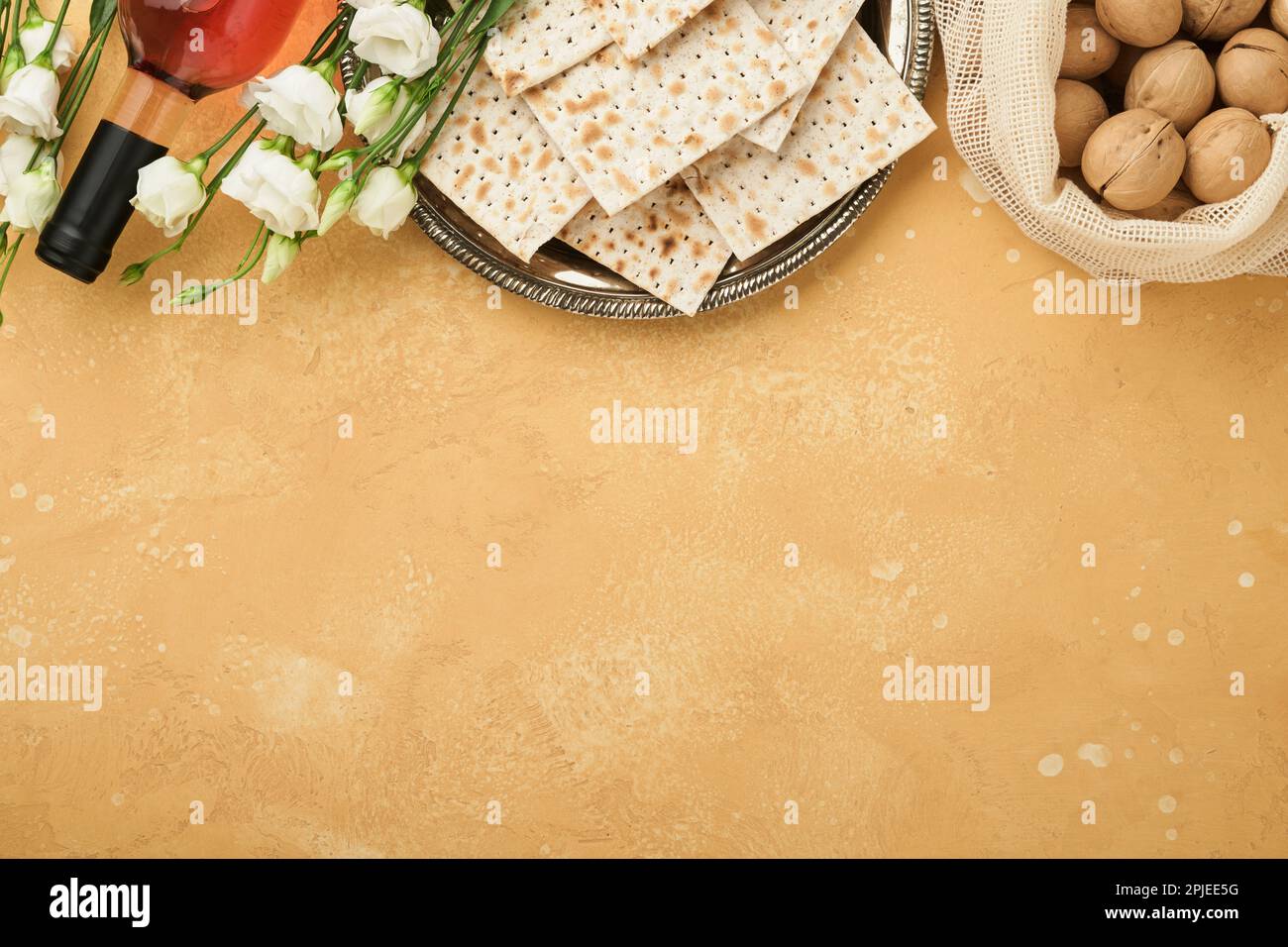 Passover Pesah celebration concept. Matzah, kosher red wine, walnut and white and yellow roses. Traditional ritual Jewish bread on sand color old tile Stock Photo
