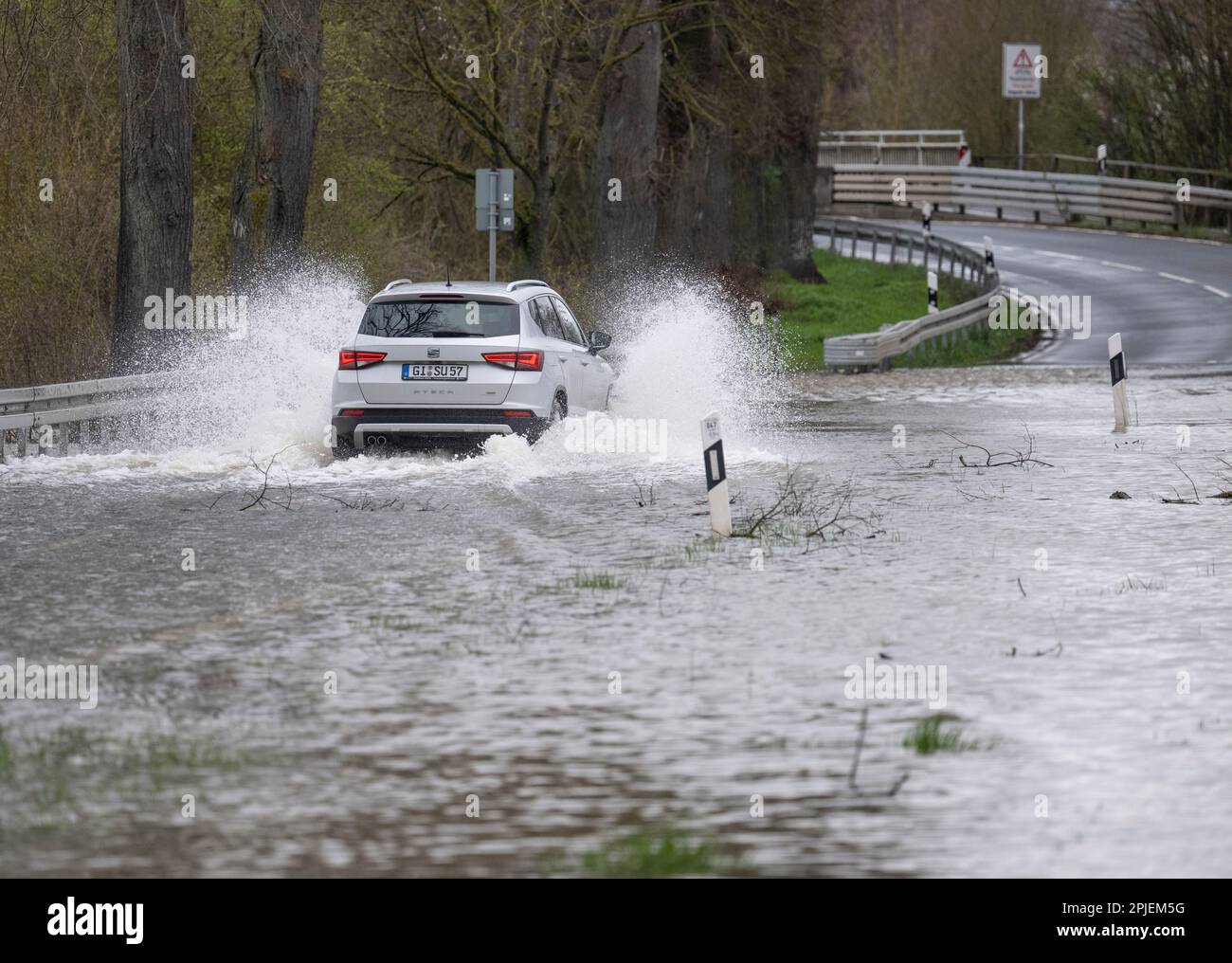 Heuchelheim, Germany. 02nd Apr, 2023. A car drives over a country road flooded by high water in central Hesse. After days of continuous rain, many rivers and streams have burst their banks. Credit: Boris Roessler/dpa/Alamy Live News Stock Photo
