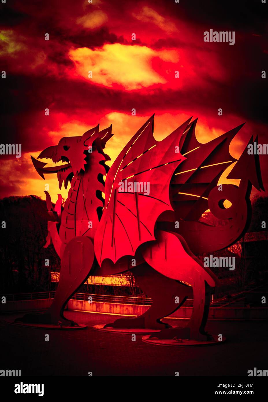 A steel sculpture of a Welsh red dragon emblazoned by a deep red fiery sky symbolizing the welsh being defiant in battle Stock Photo