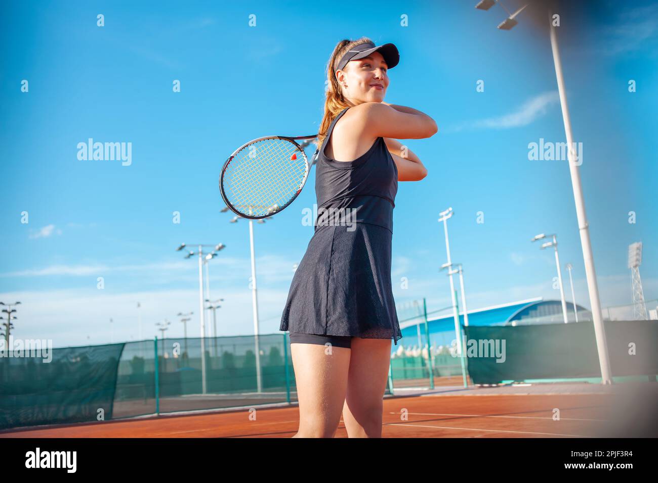 Happy preteen girls in sport outfits with tennis rackets on green