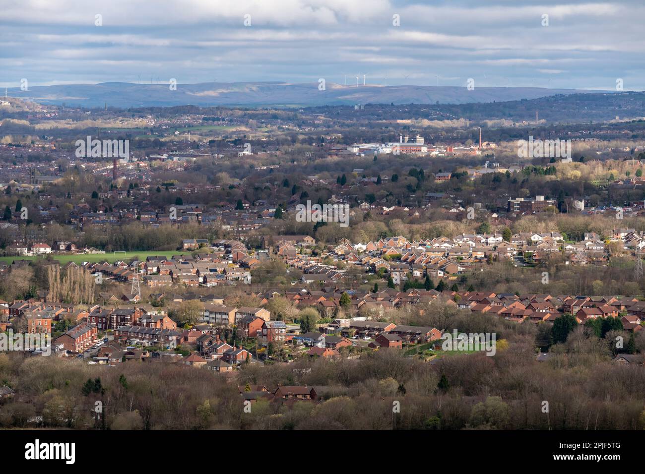 View over the town of Hyde in Greater Manchester, England with wind turbines seen on the moors in the distance. Stock Photo