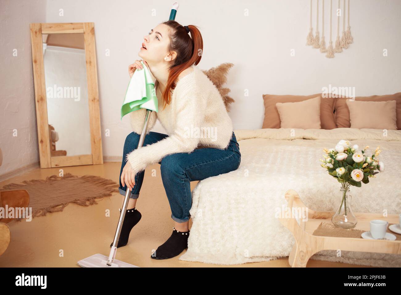 A young beautiful girl tired after cleaning. A woman sits on the bed