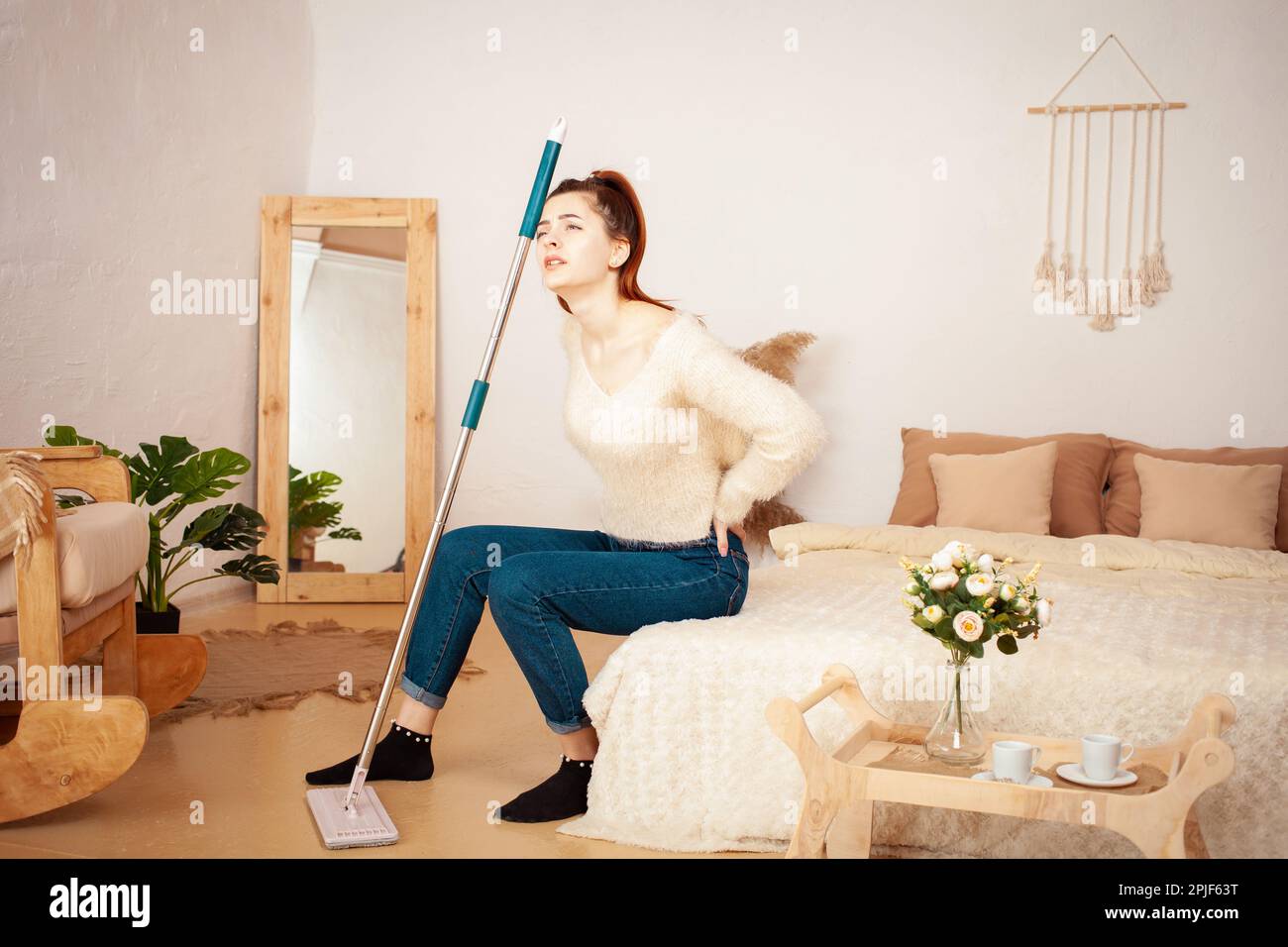A young beautiful girl tired after cleaning. A woman sits on the bed