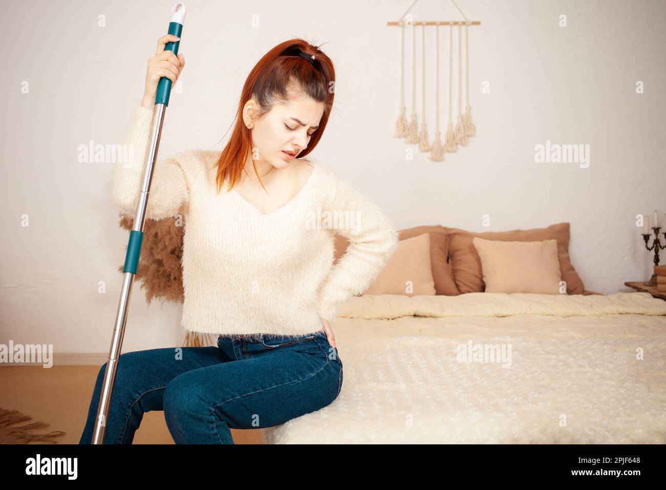 A young beautiful girl tired after cleaning. A woman sits on the bed