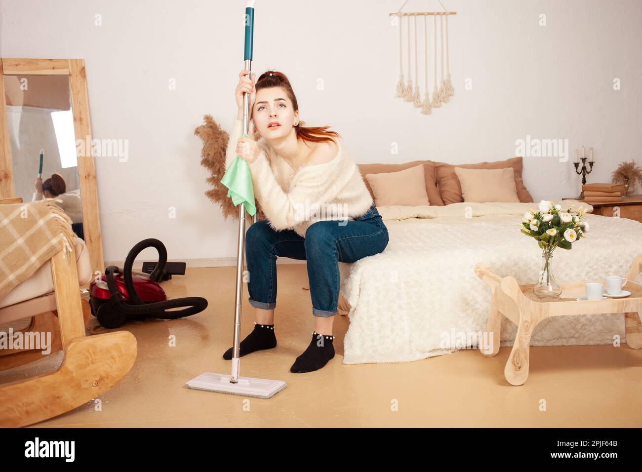 A young beautiful girl tired after cleaning. A woman sits on the bed