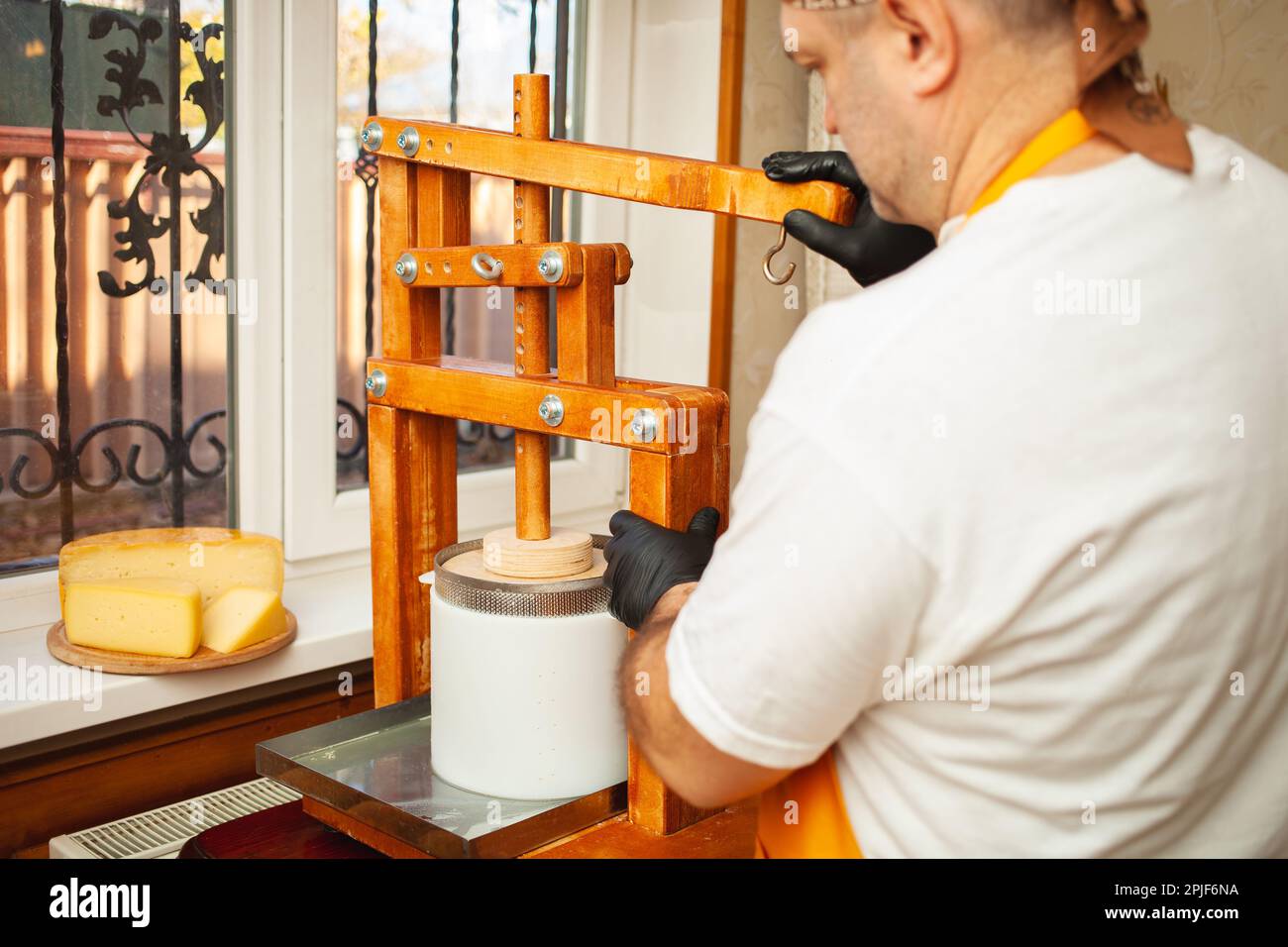 The cheesemaker puts cheese under press, whey. Home production