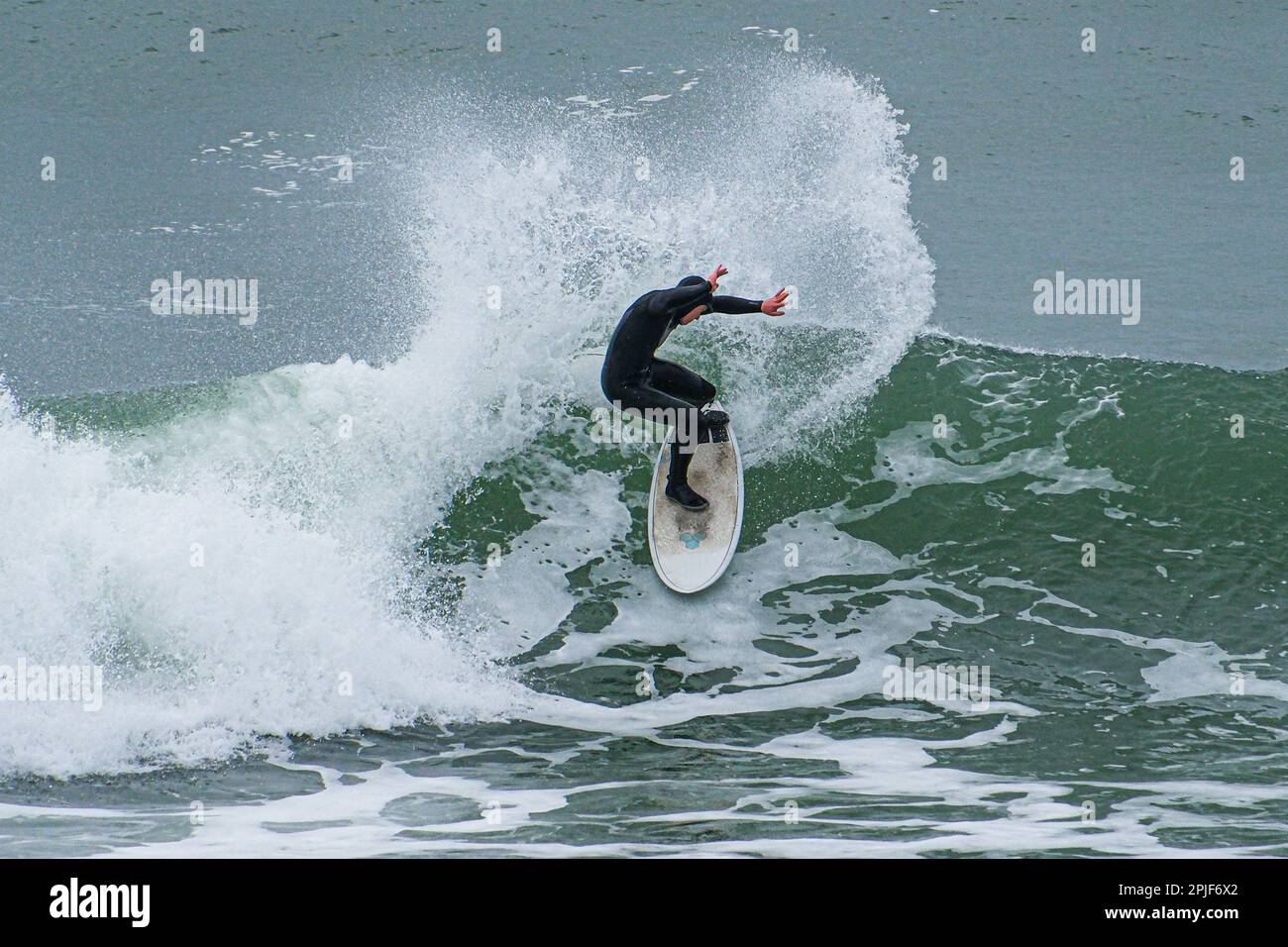 Surfer making a letter C pose as he ride the waves in Cornwall Stock Photo