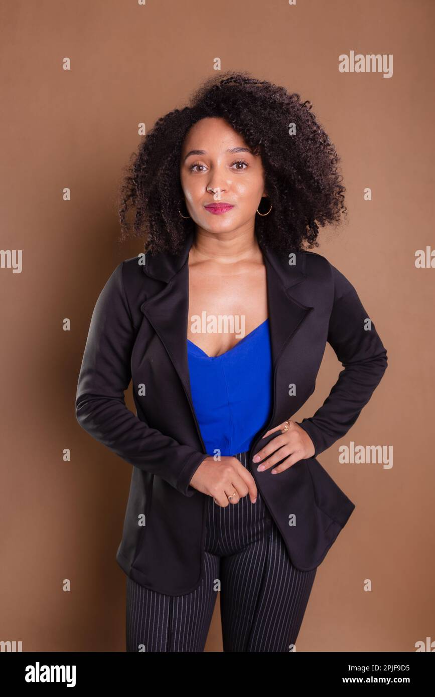 Woman dressed in black blazer standing against brown background
