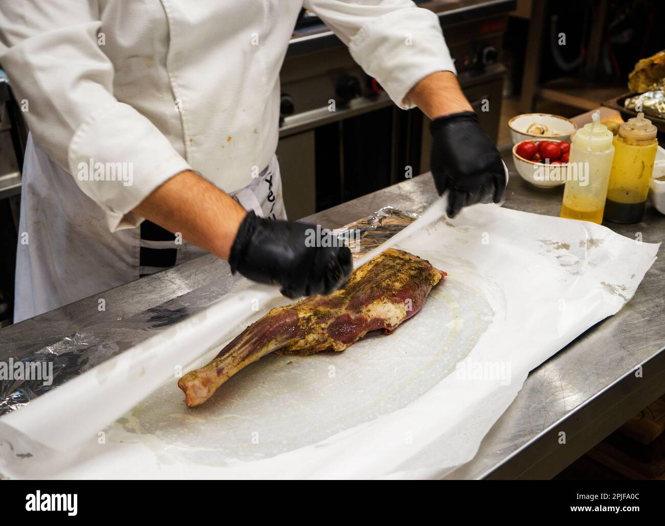 The chef also prepares lamb shank dishes. The process of cooking lamb shank male chef in a professional kitchen. Cooking meat in a Caucasian restauran Stock Photo