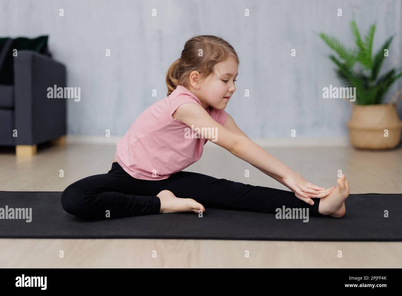 portrait of cute little girl doing stretching exercises on yoga mat at home  Stock Photo - Alamy