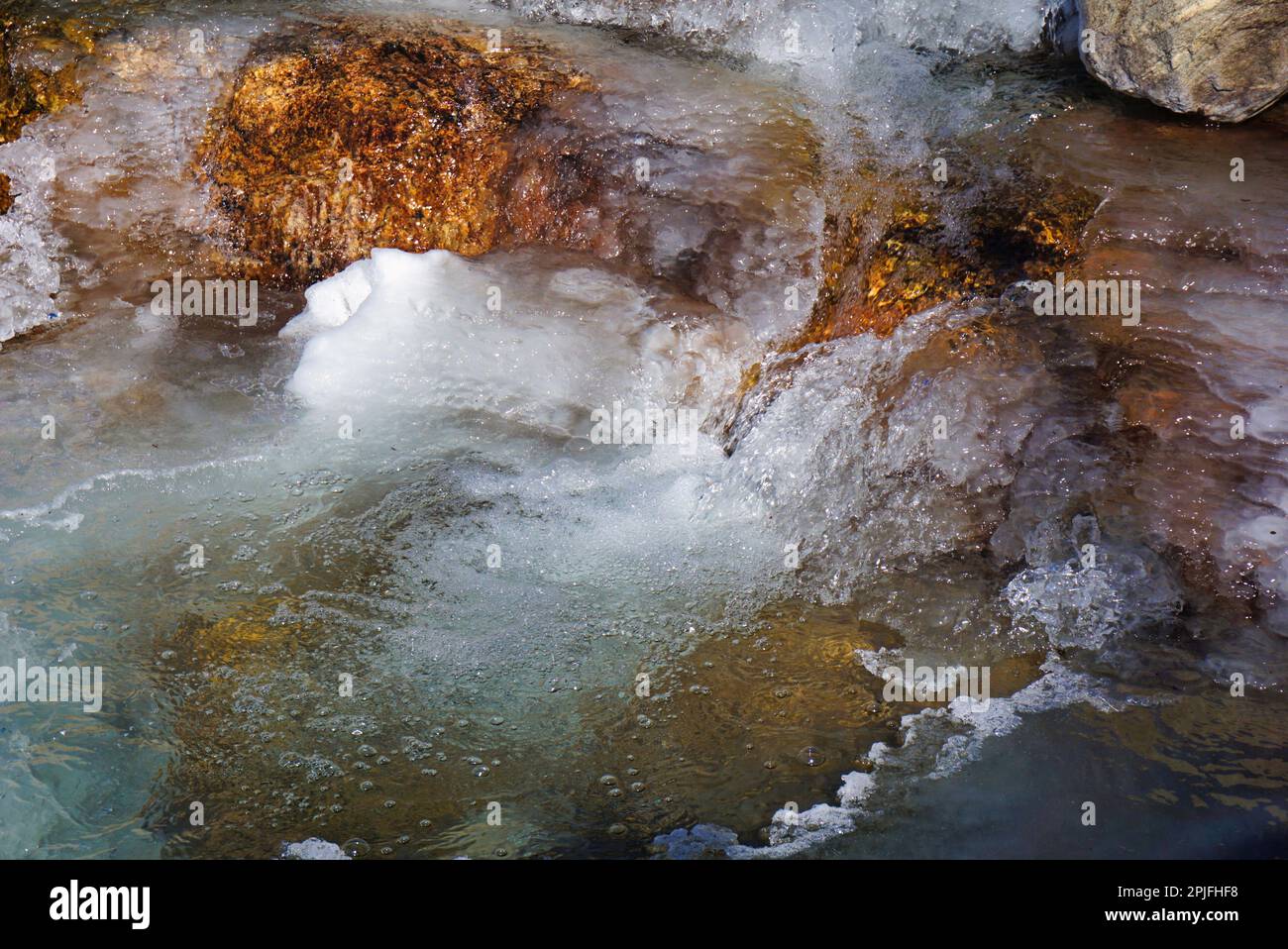 Pool at the bottom of a partially frozen waterfall, Rocky Mountains