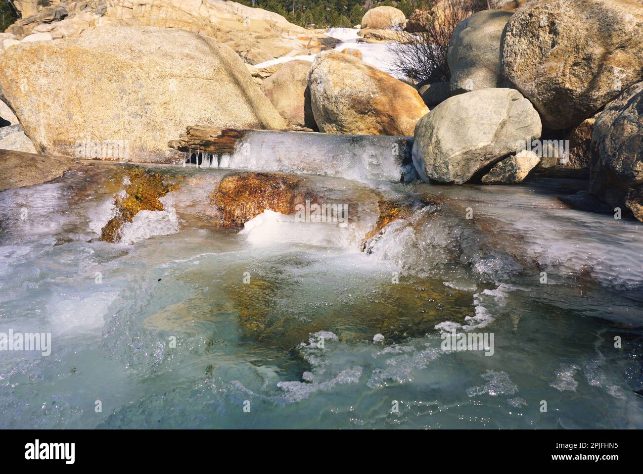 Pool at the bottom of a partially frozen waterfall, Rocky Mountains