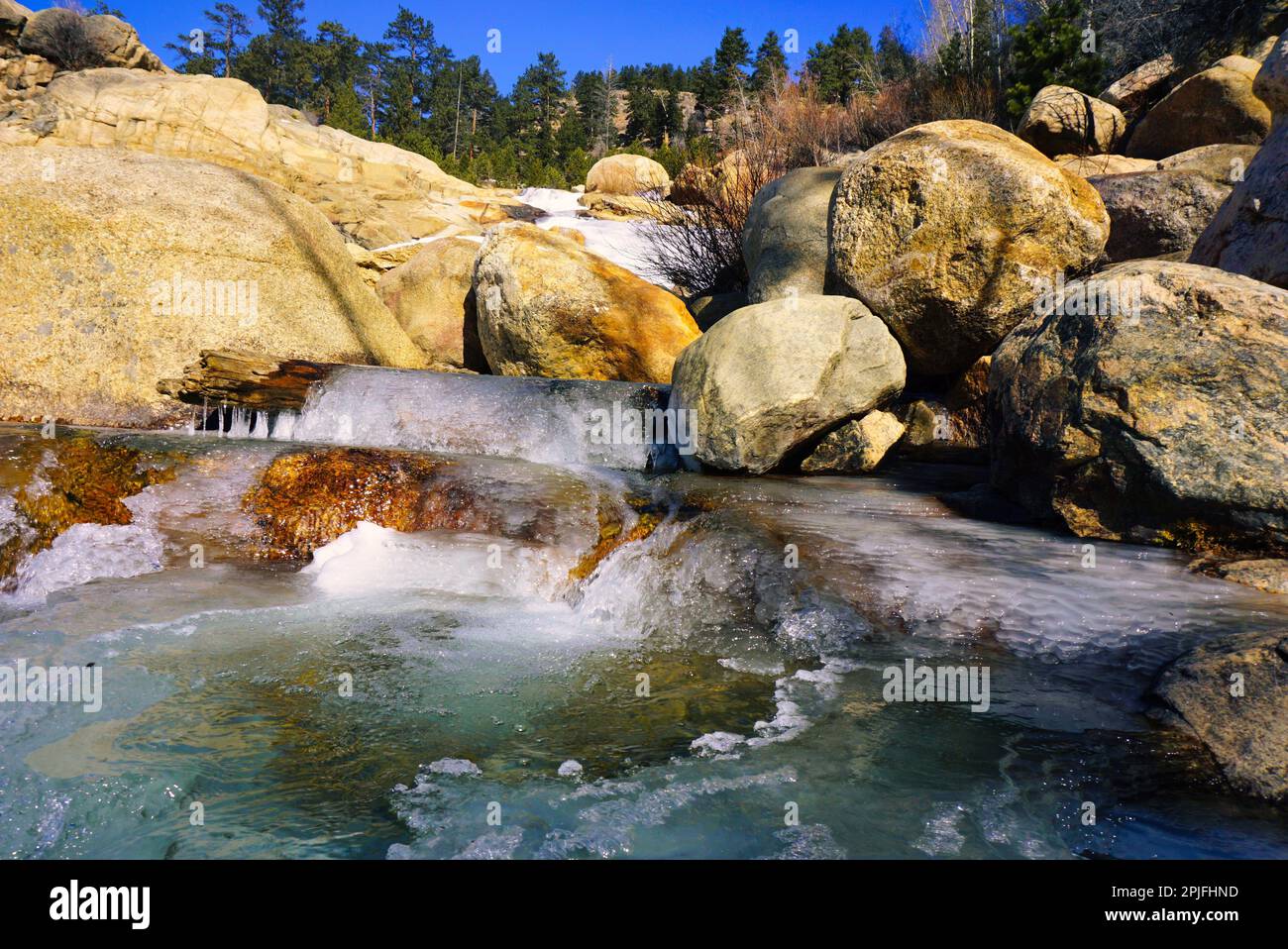 Pool at the bottom of a partially frozen waterfall, Rocky Mountains