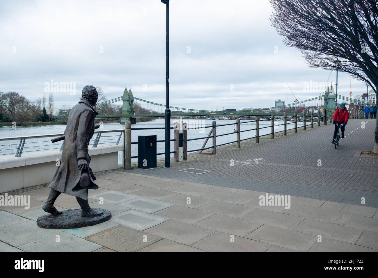 London- February 2023:London- February 2023: Hammersmith Bridge and statue on the Thames Path outside the Riverside Studios Stock Photo