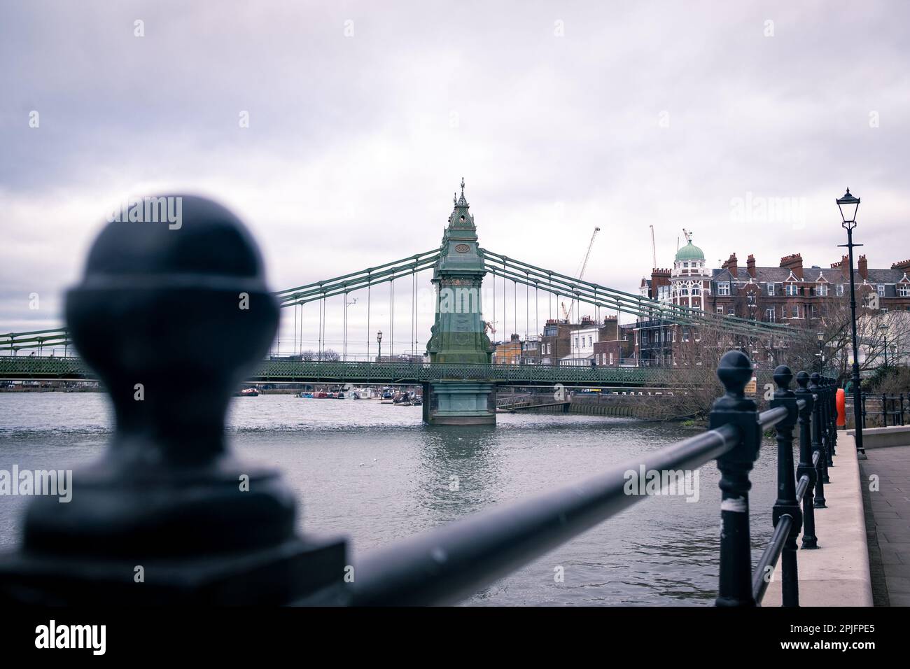 London- February 2023: Hammersmith Bridge from the Thames Path outside the Riverside Studios Stock Photo