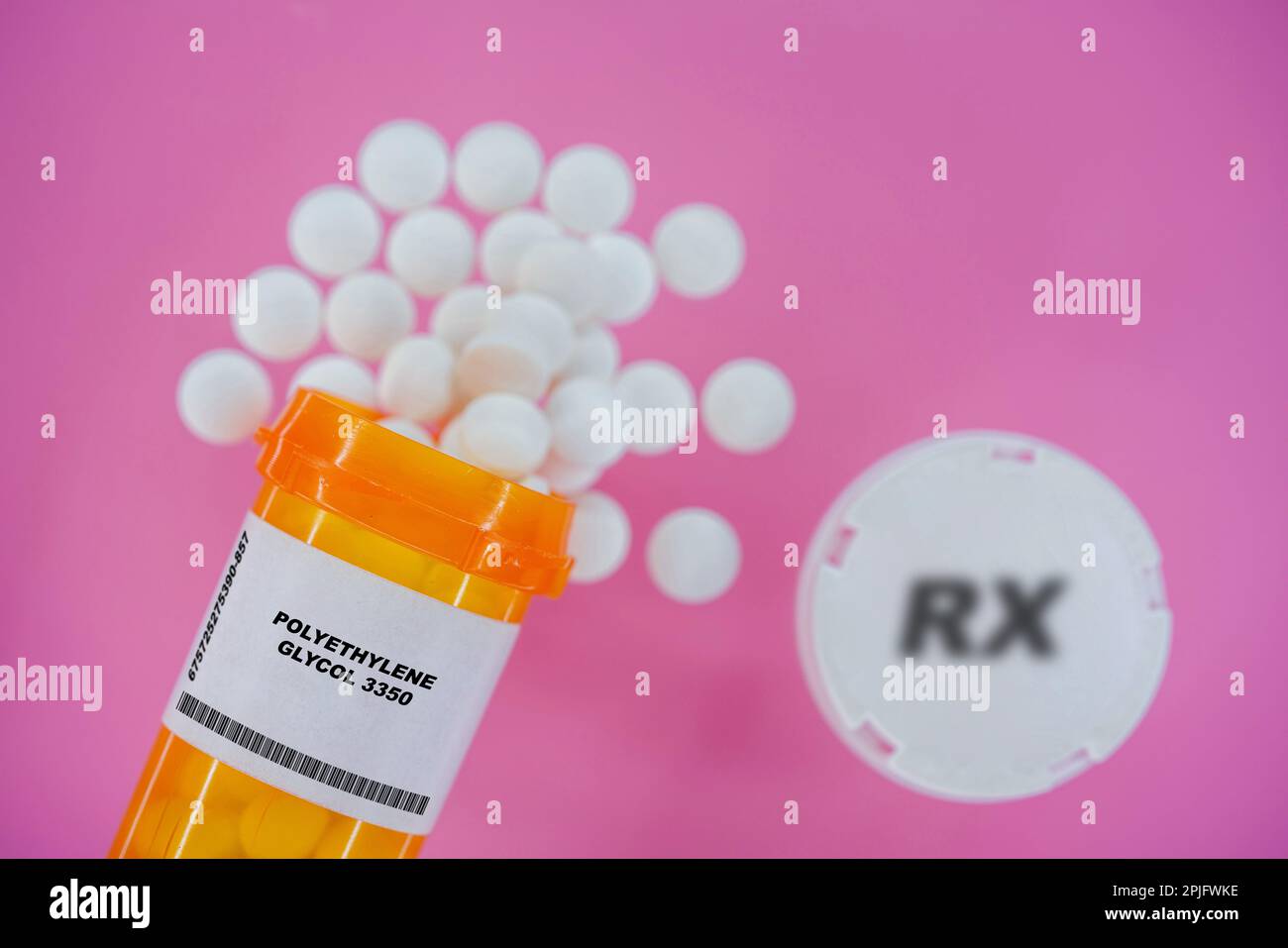 Polyethylene Glycol 3350 Rx medicine pills in plactic vial with tablets. Pills spilling   from yellow container on pink background. Stock Photo