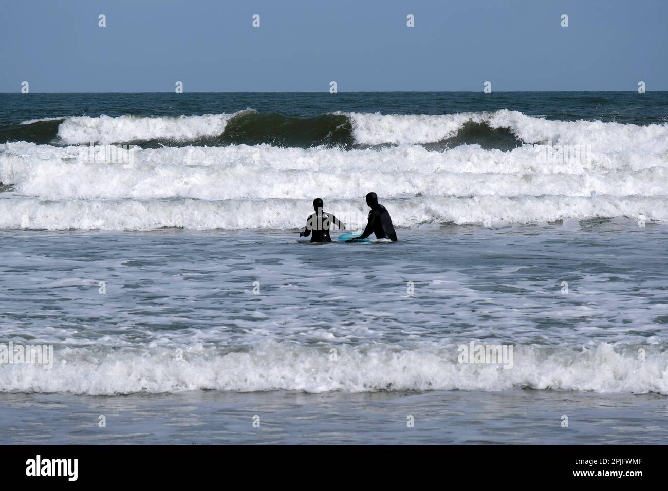 Dunbar, Scotland, UK. 2nd April 2023. People enjoying the Sunny but deceptively cold weather, along the East Lothian coastline at Belhaven Bay. Temperature around 5C in the the breeze. Surfing on the waves. Credit: Craig Brown/Alamy Live News Stock Photo