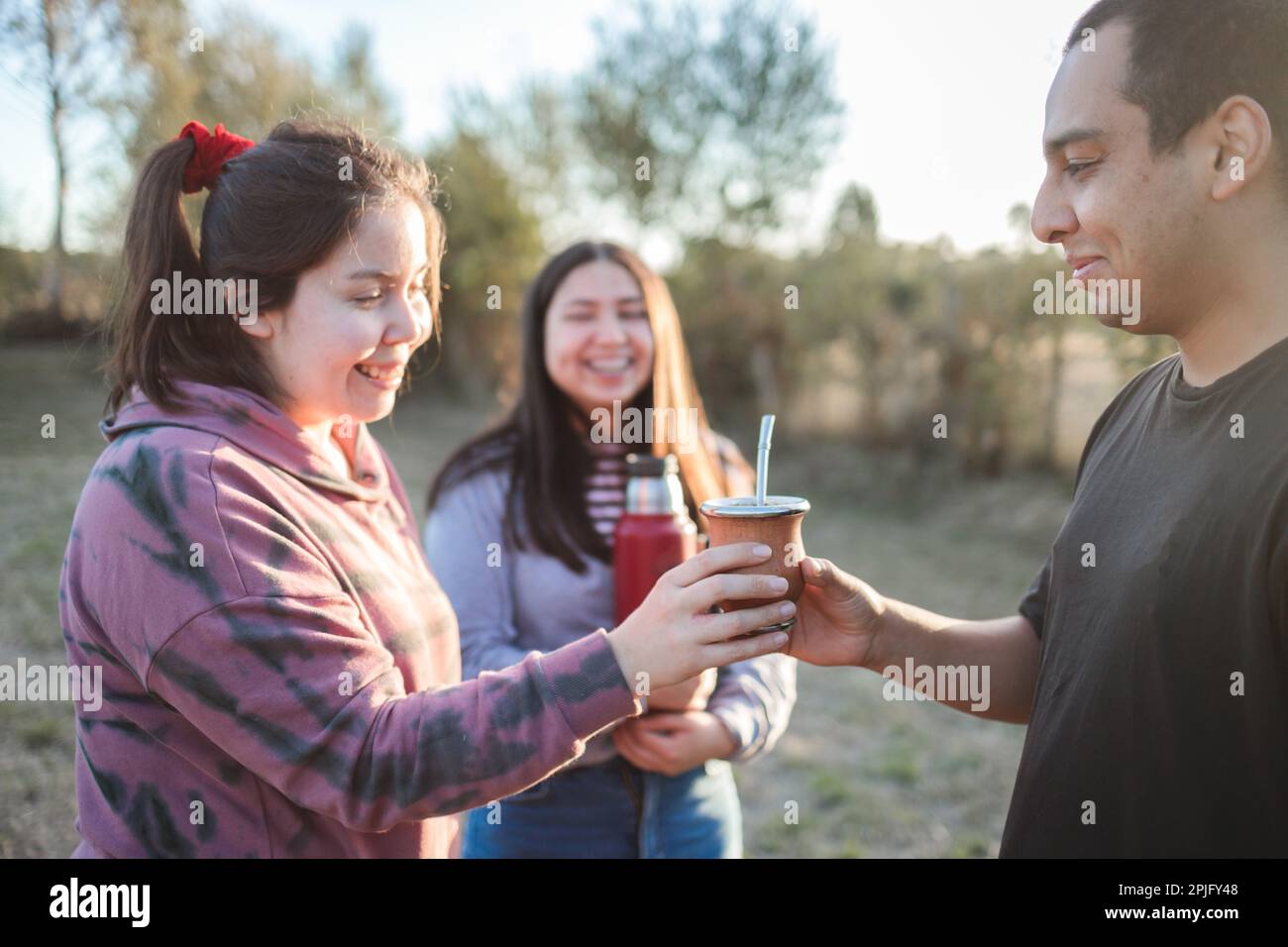 Close Up Of Smiling Friends Drinking Yerba Mate Using A Thermos With Hot  Water In The Countryside At Sunset Stock Photo - Download Image Now - iStock
