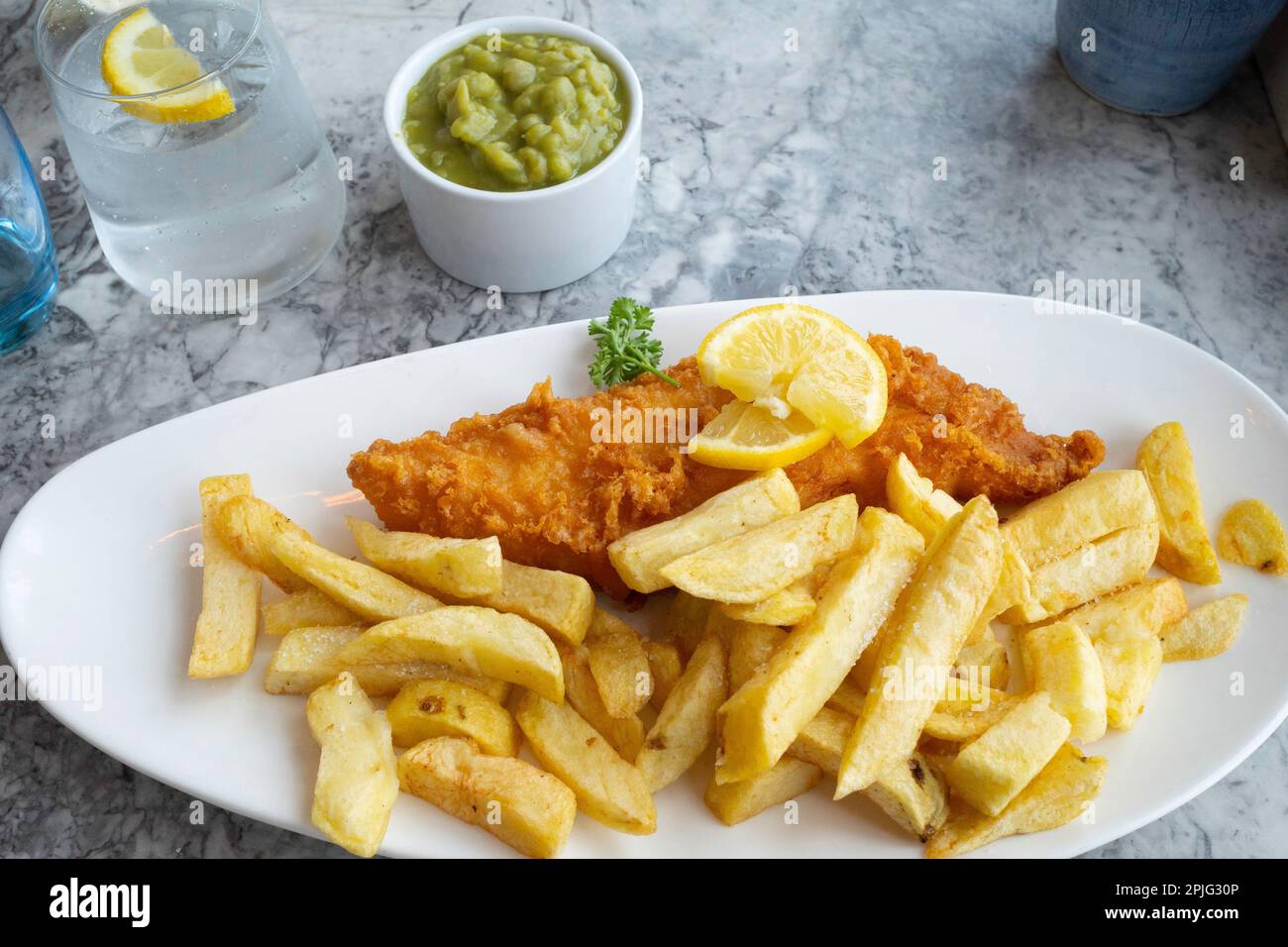 Fried battered Haddock and chips with mushy peas and a glass of