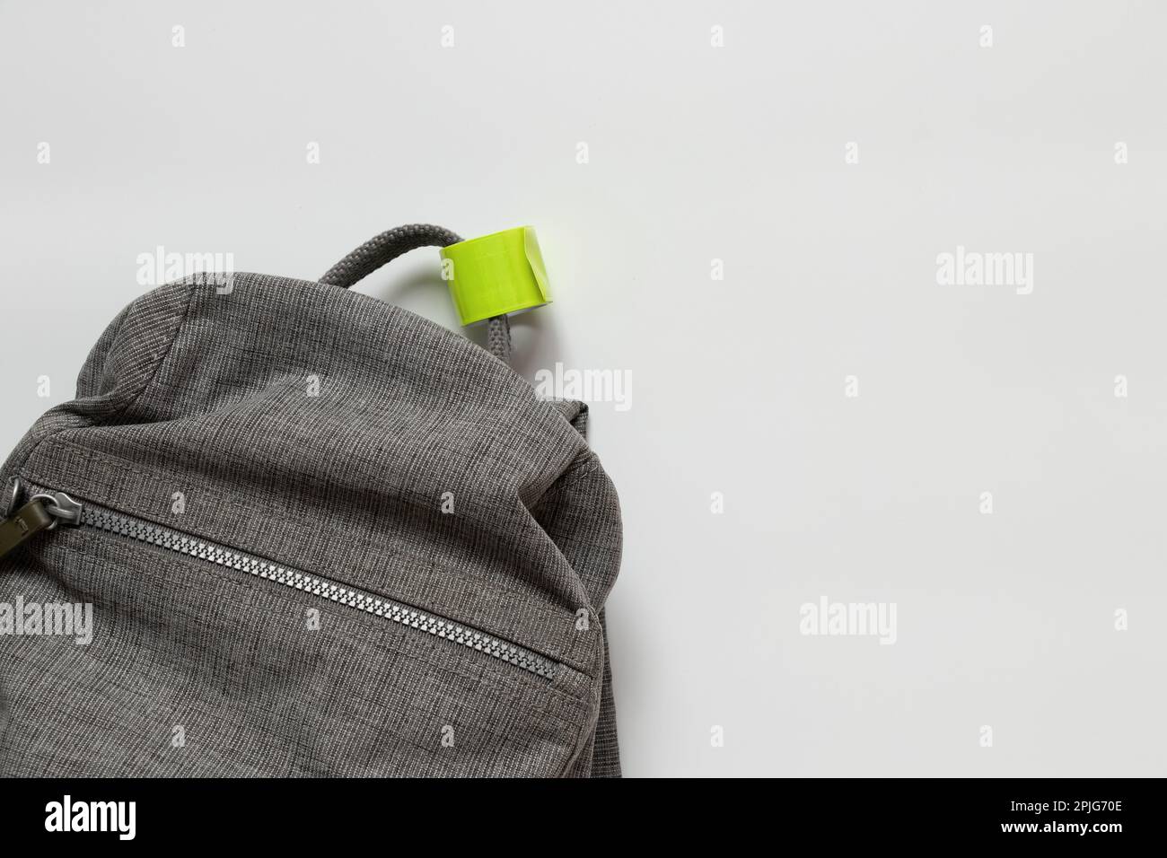 reflective tape hangs on the handles of a gray backpack on a white