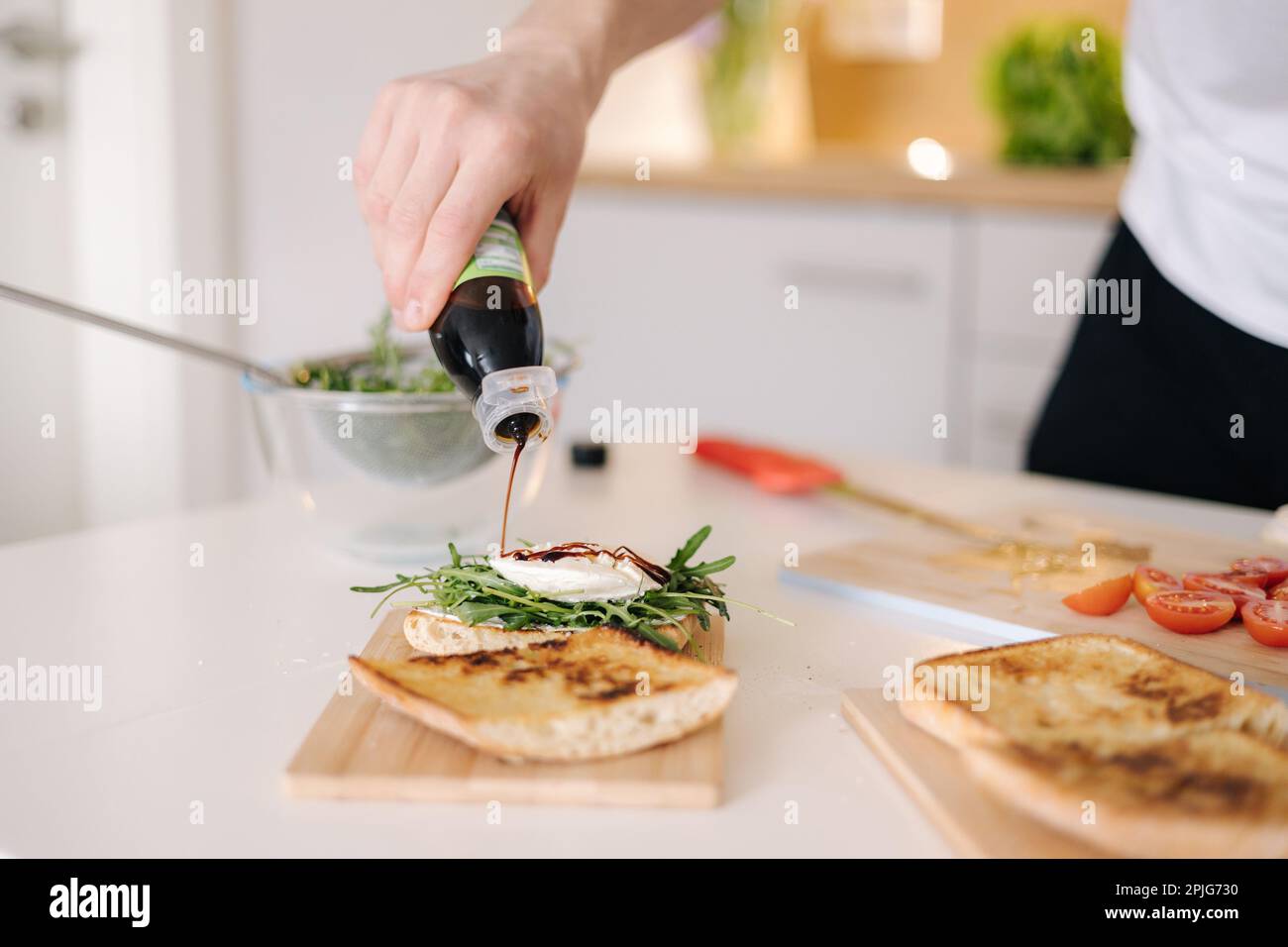 Process of pouring balsamic vinegar on sandwich. Baguette arugula and