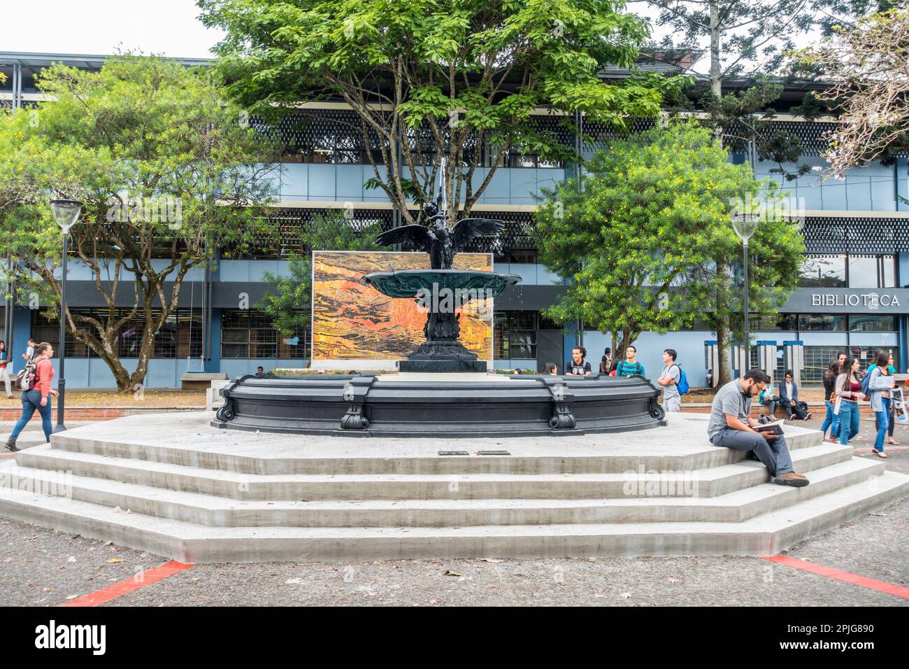 Students at the University of Costa Rica sitting around a fountain and a large mosaic are work. Stock Photo