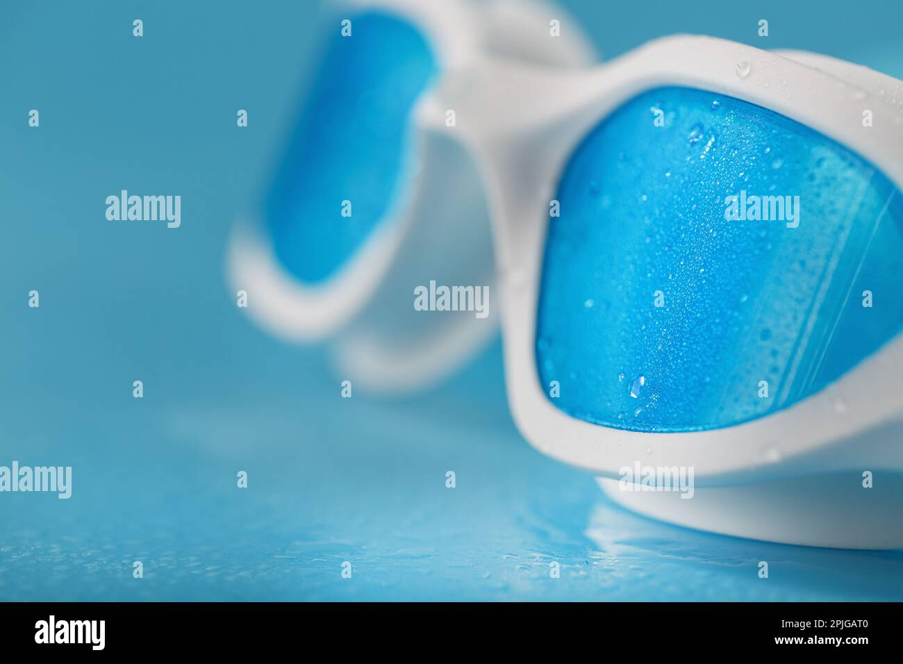 White swimming glasses with a blue lens on a blue background Stock Photo