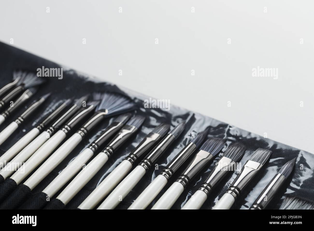 Brushes, palette knives in a pencil case on a white canvas background. top view with free space Stock Photo