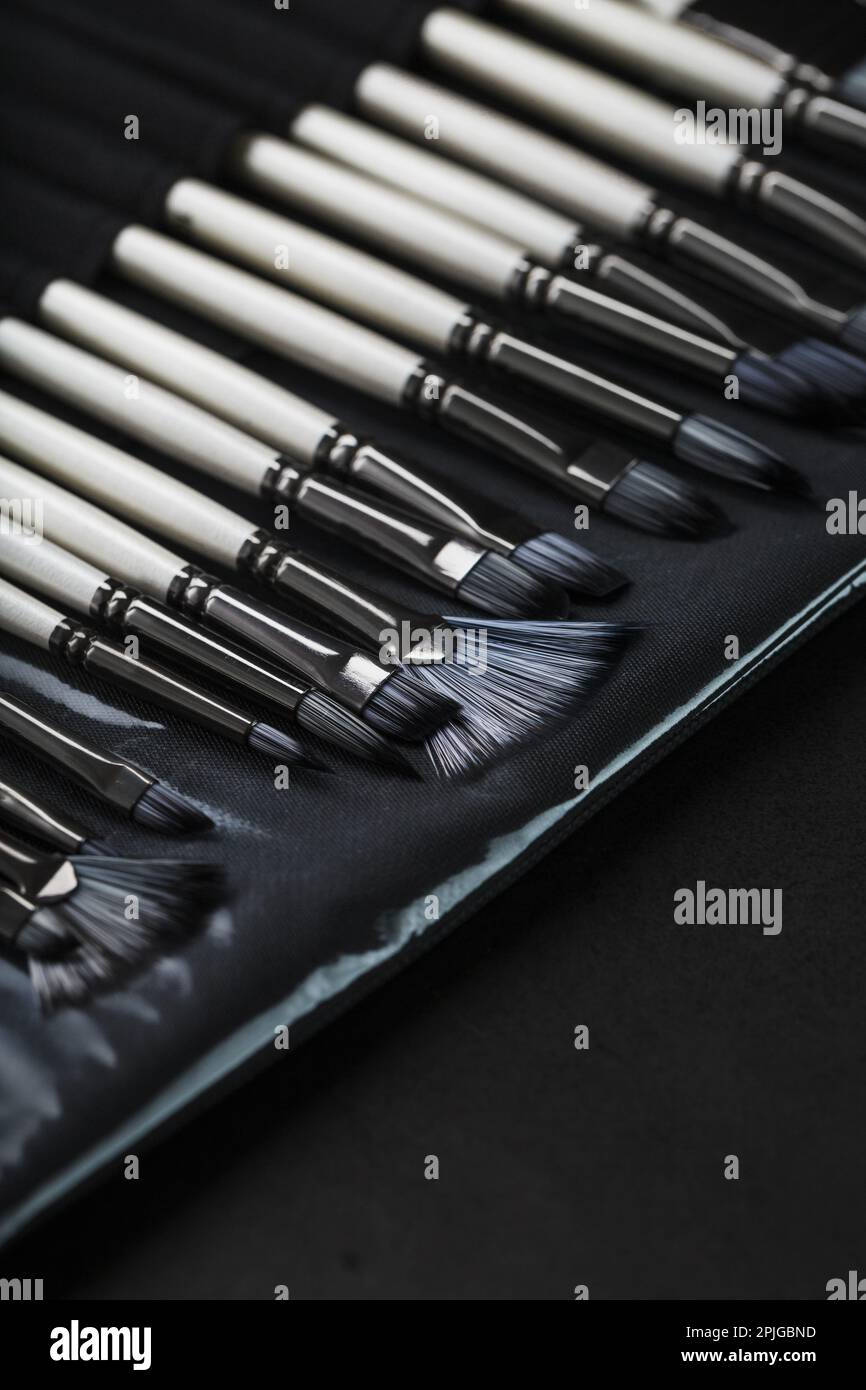 A set of oil brushes and palette knife isolated on a black background, Close-up Stock Photo