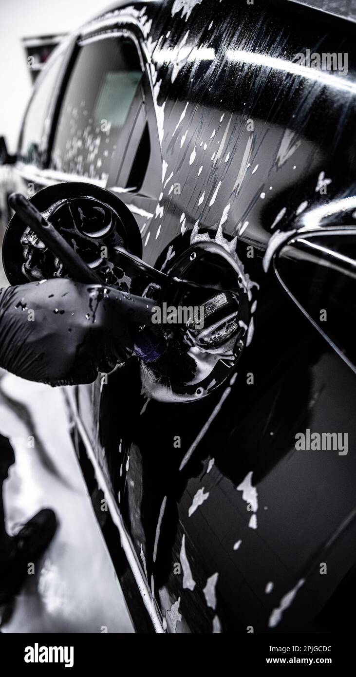 Car detailing studio or car wash employee cleans the fuel filler area