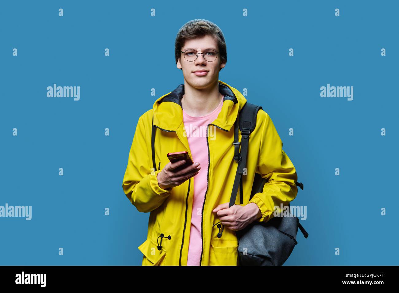 Trendy young male in yellow jacket hat using smartphone on blue background  Stock Photo - Alamy
