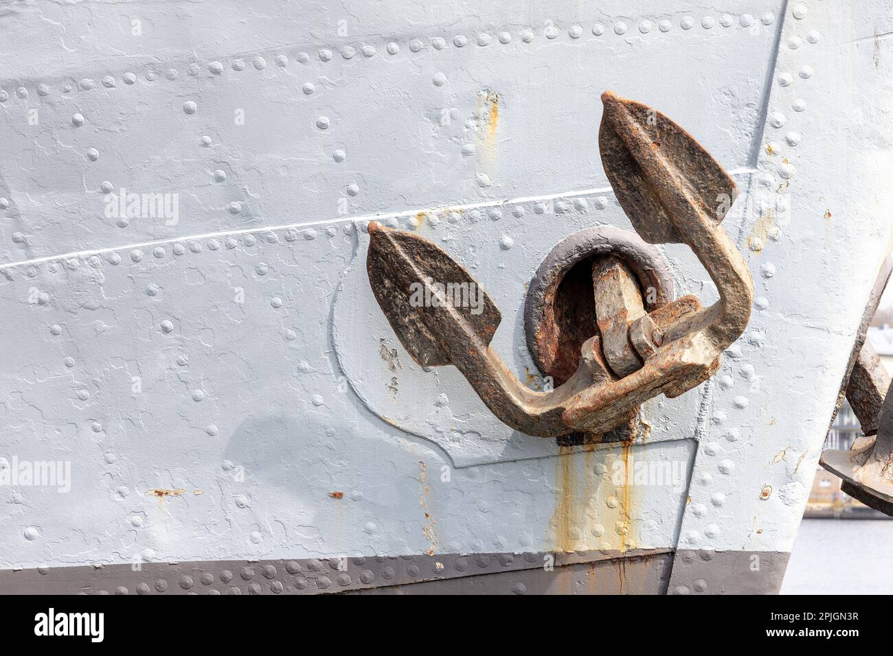 View of a rusted ship's anchor on the anchor hole of a gray ship on the ...